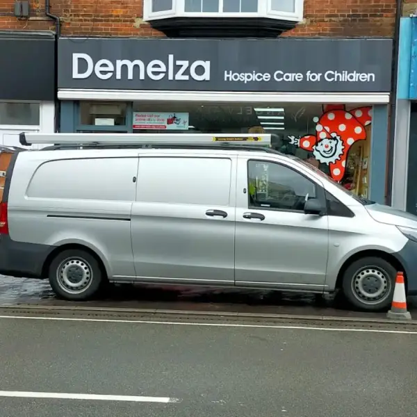Van outside a high-street charity shop for a blocked internal drain