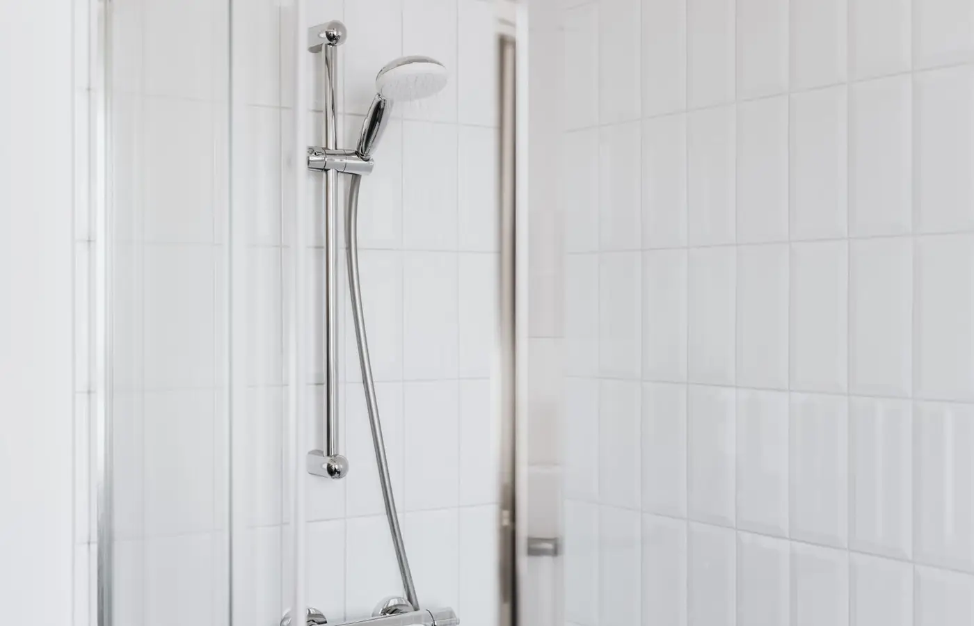 Stylish shower setup with chrome fixtures and clean white tiles.