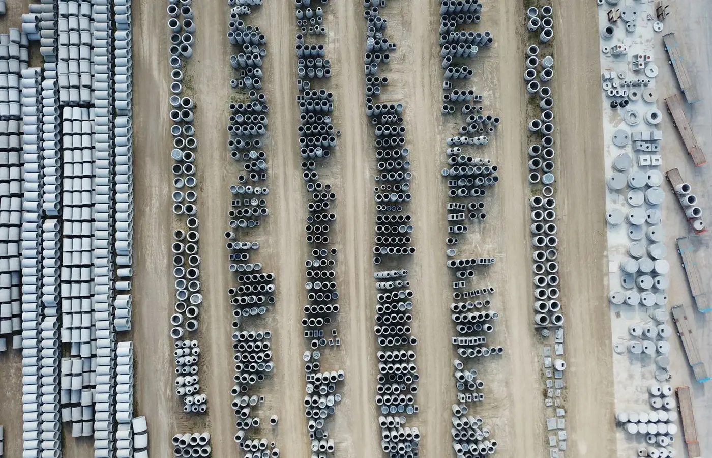 Drone shot of an organized outdoor concrete manufacturing facility with various pipes.