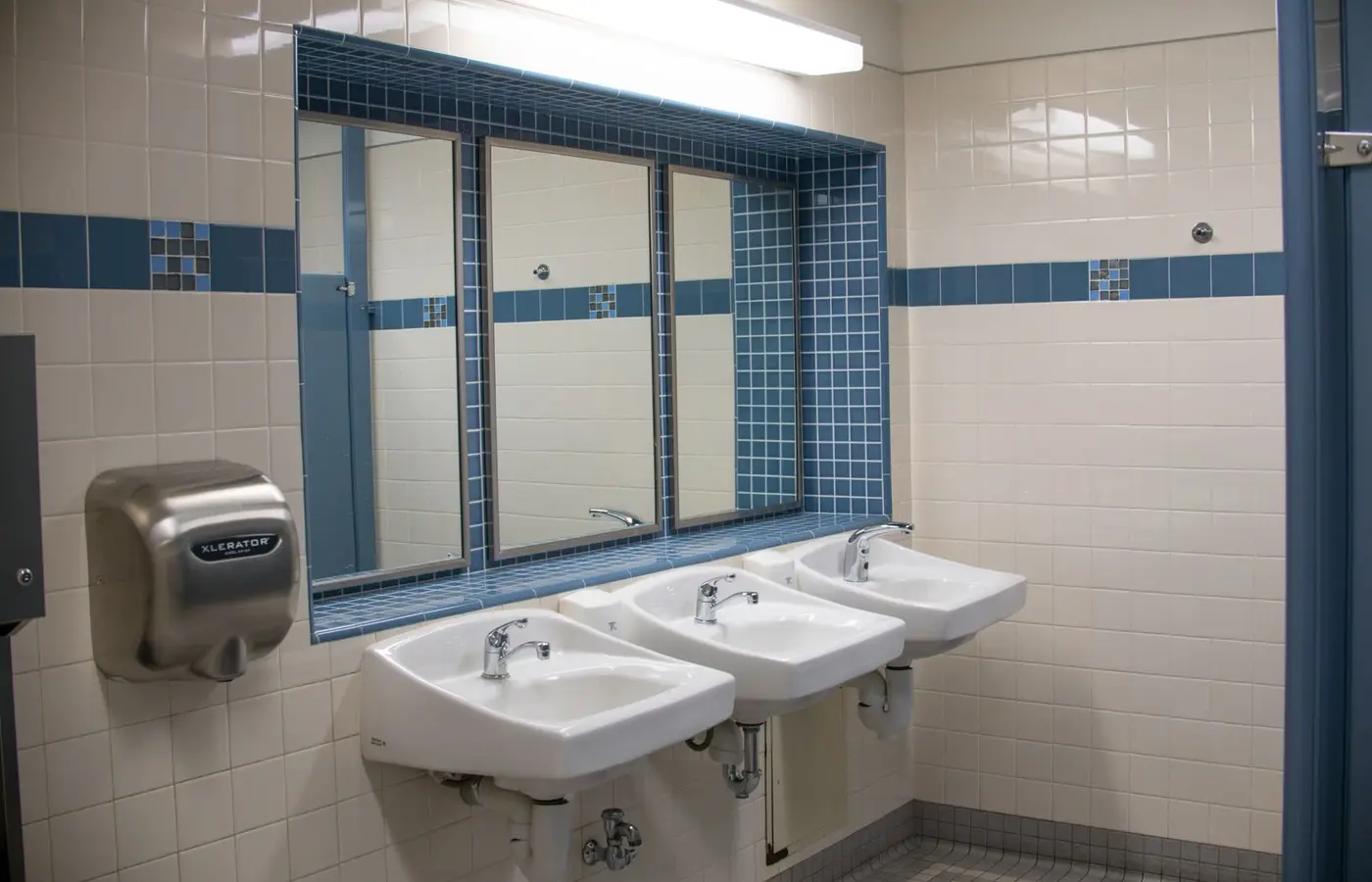 Clean and bright public bathroom with sinks, mirrors, and a hand dryer.