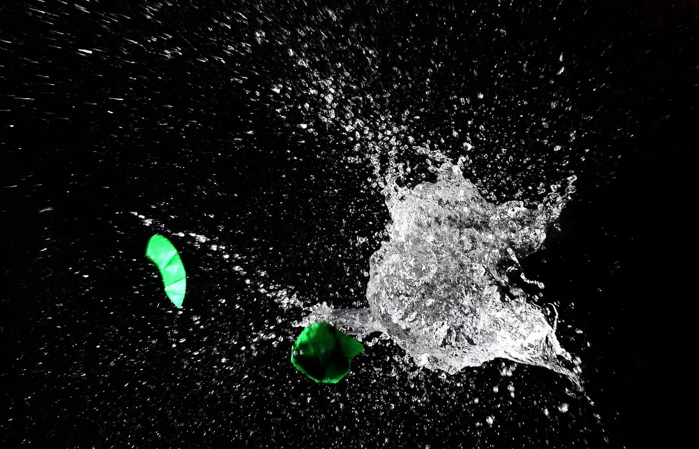 High-speed capture of a water balloon bursting, revealing dramatic splash against a dark background.
