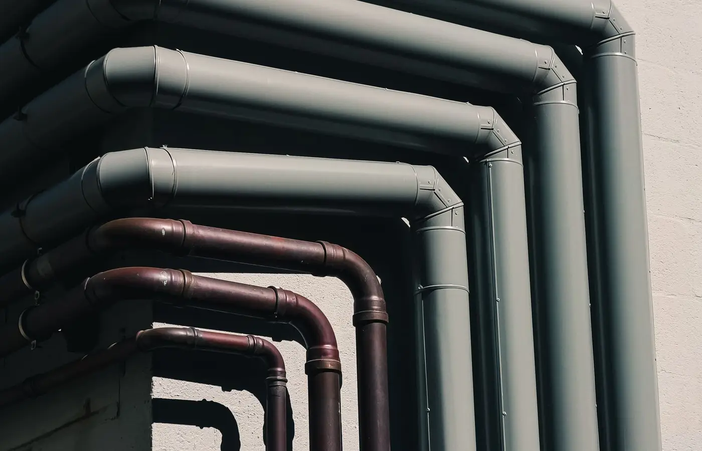 Close-up of industrial pipes forming a pattern on a building's exterior wall, shot outdoors.