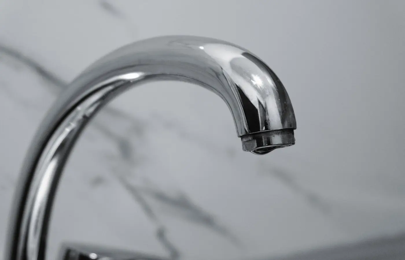 Close-up of a chrome tap against a marble background.
