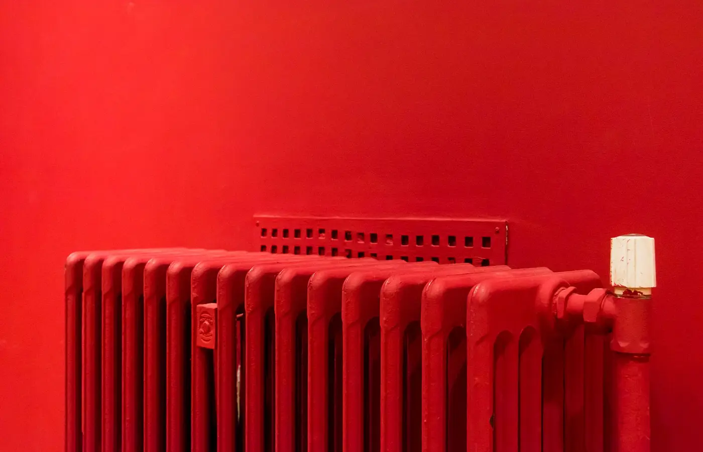 A red radiator fitted against a matching red wall.