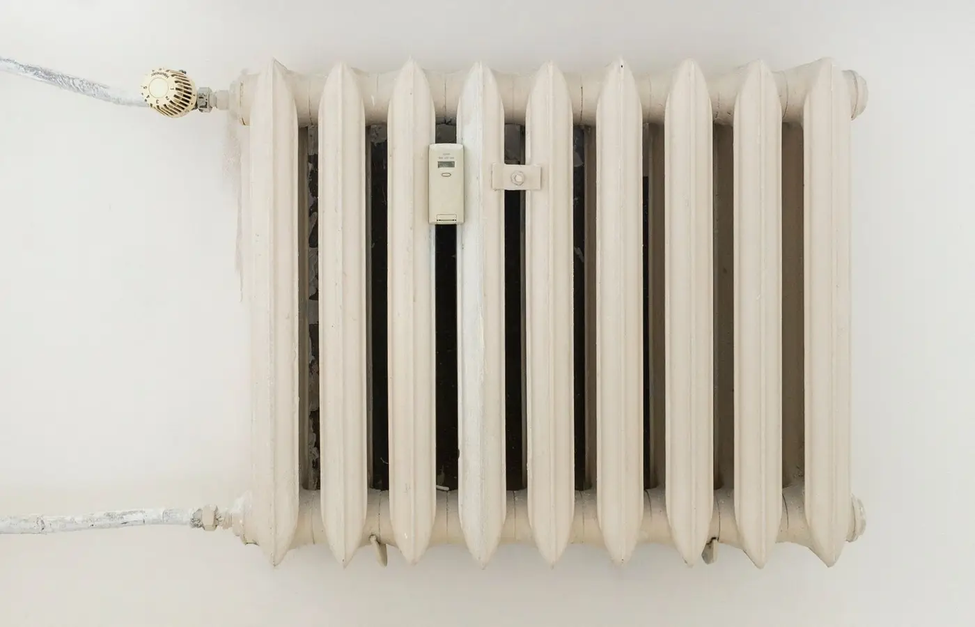 A classic white metal radiator on a plain wall.