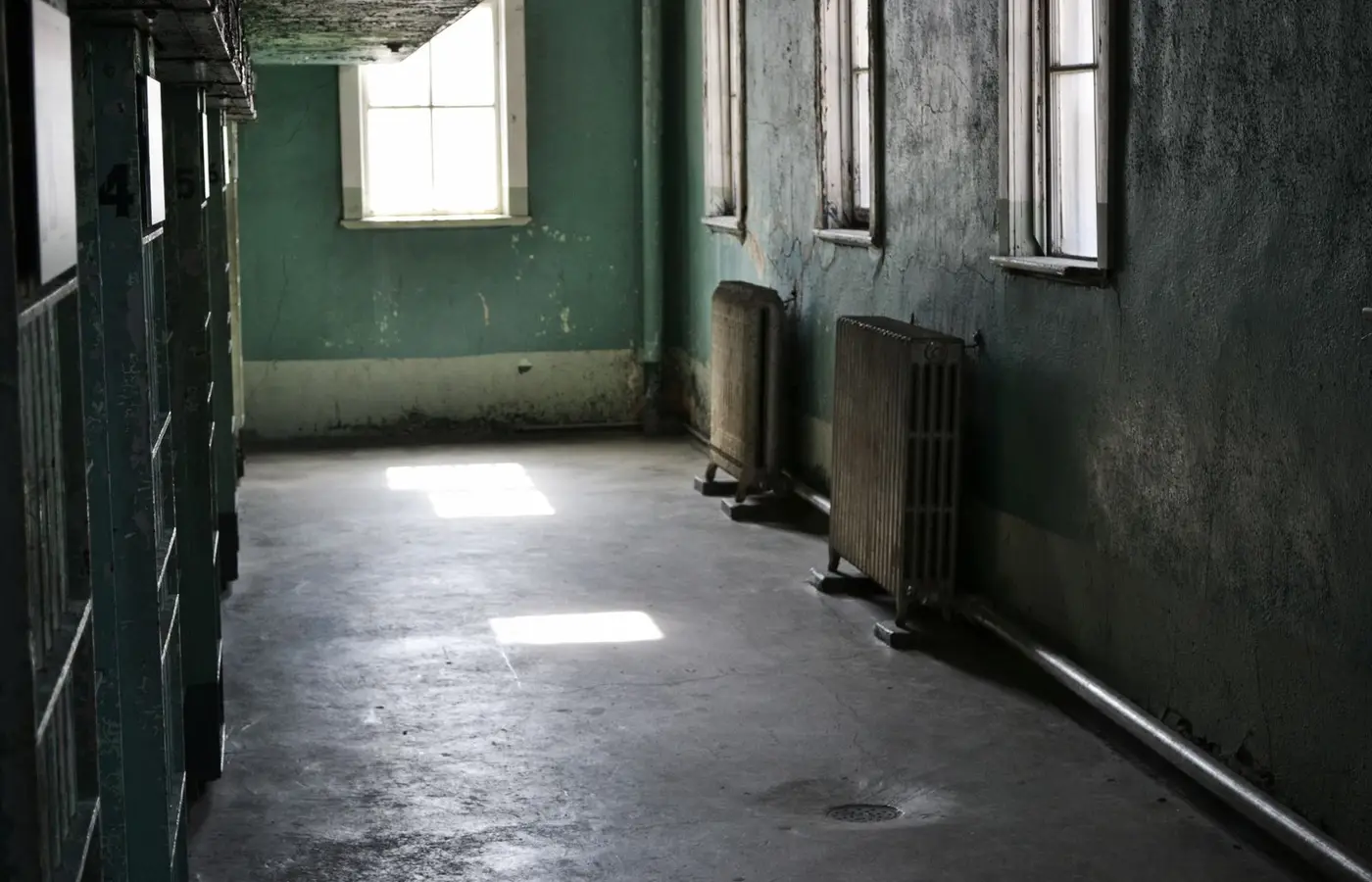 An empty hallway in an abandoned building with sunlight streaming through windows.
