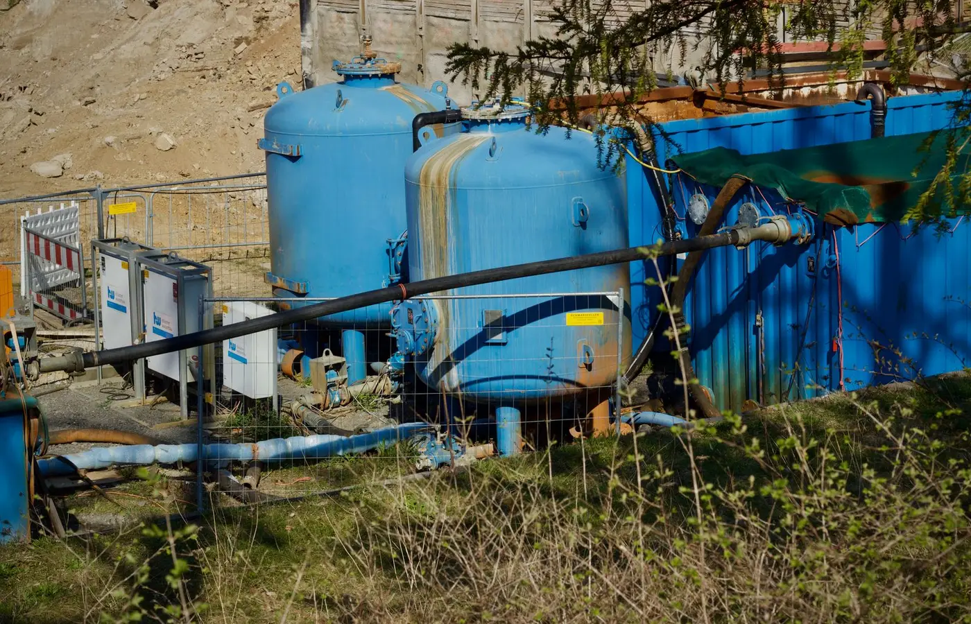 Outdoor industrial water filtration plant with large blue tanks under sunlight.