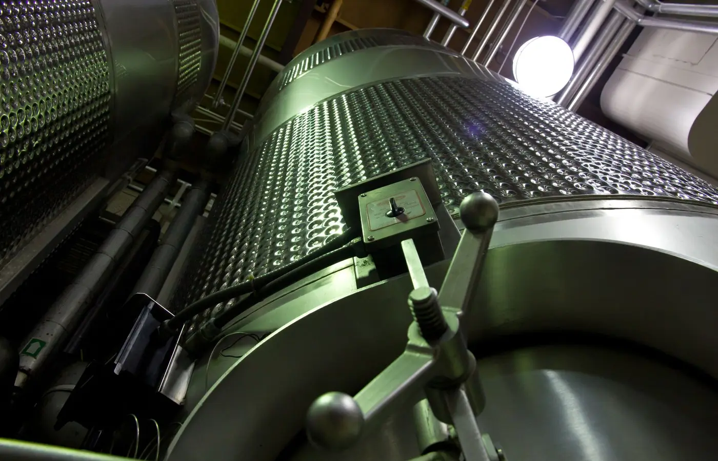 Low-angle shot of large stainless steel tanks inside a modern industrial facility.